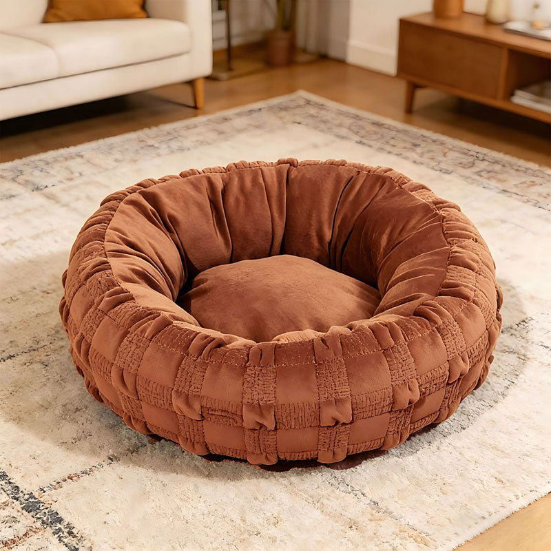Small white dog sitting in green woven donut pet bed