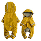 Miniature schnauzer wearing yellow fleece-lined hooded raincoat outdoors in the rain