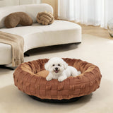 Woven donut dog bed in brown on a living room rug