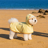 Dog wearing yellow duck poncho raincoat - side view with transparent hood
